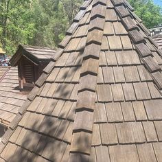 the roof of a house with many shingles and trees in the backgroud