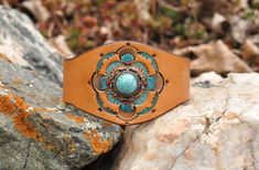 The centerpiece on this cuff is a delicate vintage turquoise and silver ring made by Taxco.  Mounted to the leather, the piece is surrounded by a floral stamped design accented by turquoise and red paint.   made on premium veg tan leather, the cuff is 1 3/4" wide at the center, and 3/4" wide at the snap closure. Gift Turquoise Ring With Concho, Unique Turquoise Ring With Concho For Gift, Bohemian Turquoise Hand Painted Jewelry, Turquoise Bohemian Hand Painted Jewelry, Vintage Hand Painted Brown Jewelry, Hand Painted Brown Vintage Jewelry, Vintage Brown Hand Painted Jewelry, Brown Hand Painted Vintage Jewelry, Western Style Stamped Turquoise Ring Gift