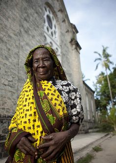 a woman in a yellow and black dress is standing by a church