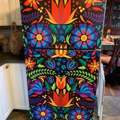 a brightly painted refrigerator in a kitchen with white cabinets