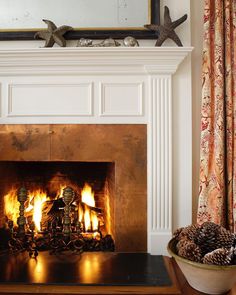 a fire place in a living room next to a mirror and window with curtains on the windowsill