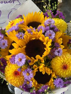 a bouquet of sunflowers and purple daisies