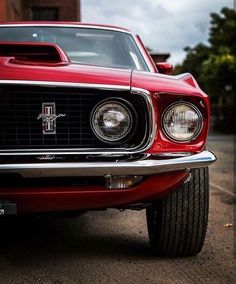 the front end of an old red mustang