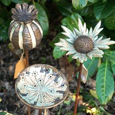 two metal sunflowers sitting next to each other on top of a dirt ground