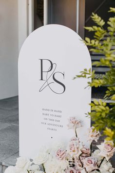 a white grave with flowers in front of it and a sign that says p & s