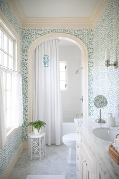 a white bathroom with blue and green wallpaper