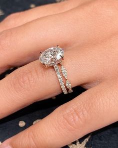 a woman's hand with a diamond ring on top of her finger and the other hand holding an engagement ring