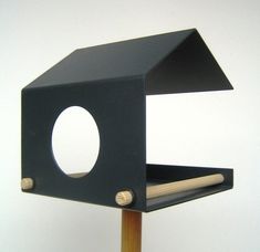 a black bird house with a wooden stick sticking out of it