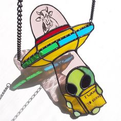 a stained glass necklace with an alien spaceship on it's side and the word i want to fly