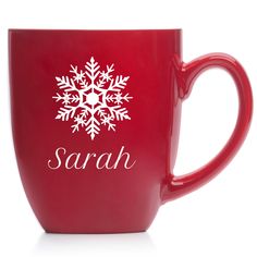 a red coffee mug with a snowflake design on the front and word sarah written in white