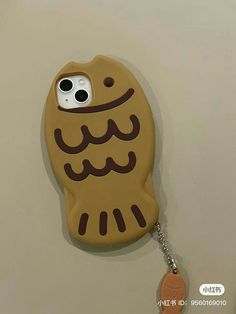 a cell phone case with an owl on it hanging from a hook attached to a wall