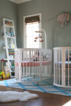 a baby's room with two cribs and a rug on the floor