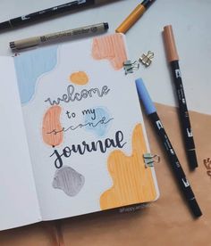 an open notebook with the words welcome to my journey written on it next to some markers and pencils