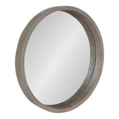 a round mirror on the wall with a metal ring around it's edge,