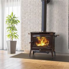 a wood burning stove in a living room next to a potted houseplant