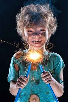 a young boy holding a sparkler in front of his face