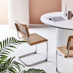 two chairs sitting at a round table in a room with pink walls and white carpet