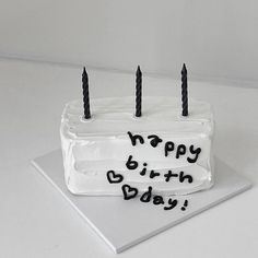 a birthday cake with white frosting and black candles on it that says happy birth day