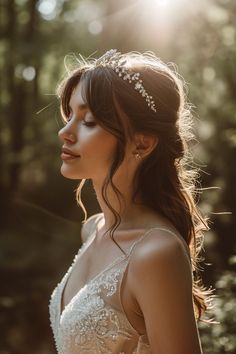 a woman wearing a tiara in the woods with sunlight shining through her hair and makeup