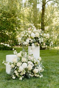 a wedding cake with white flowers on it and greenery in the backgroun