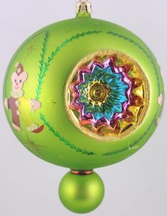 a green ball ornament with a colorful design on the front and side, hanging from a chain