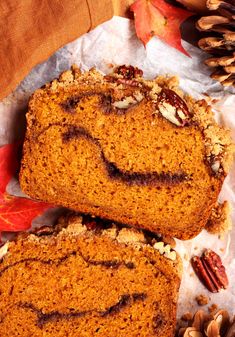 two slices of pumpkin bread sitting on top of a piece of wax paper next to some nuts