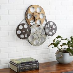 there is a clock made out of old movie reels on the wall next to a potted plant