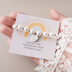 Surprise your sweet flower girl with our adorable flower girl bracelet - a wonderful thank-you gift! This child-sized bracelet features alternating gold-plated beads between each faux pearl, adorned with a dainty monogram charm available in gold or silver for that extra touch of personalization. Elegantly packed with a thank-you card featuring a cute rainbow design and a gift box, these stretchy bracelets are designed to fit most girls aged 3-10. They make for an ideal keepsake, expressing your White Flower Charm Bracelet For Wedding, White Wedding Bracelets With Flower Charm, White Wedding Bracelet With Flower Charm, White Flower Bracelet For Mother's Day, White Flower Bracelets For Mother's Day, Cute White Jewelry For Bridesmaid Gift, Cute White Pearl Bracelet For Gift, Hypoallergenic White Bracelet For Bridesmaids, Cute White Jewelry For Bridesmaids