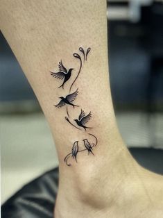 a small tattoo on the ankle of a woman's foot with birds flying around it