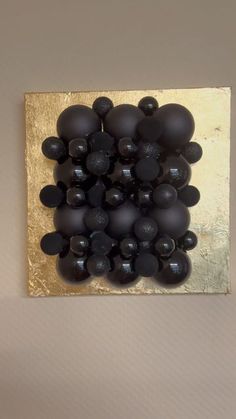 black balls are arranged in a square on a gold and white tile wall hanging from the ceiling