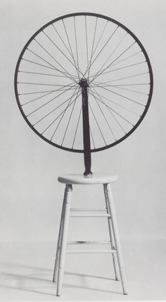 an old fashioned bicycle wheel sitting on top of a stool