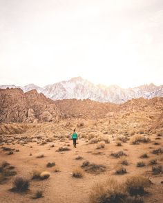 a person walking through the desert with mountains in the background