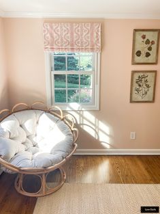 a room with pink walls and wooden flooring has a swing chair in the corner