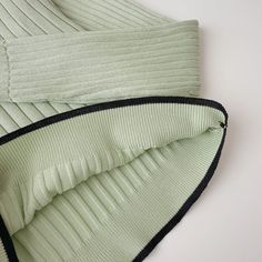 an up close shot of some green sweaters on a white surface with black stitching