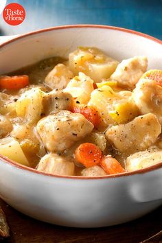 a white bowl filled with chicken and dumplings on top of a wooden cutting board