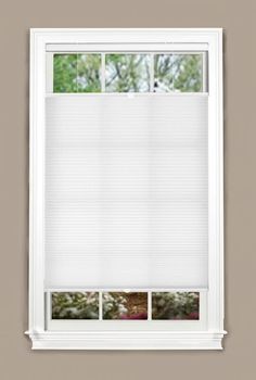 an open window with white blinds in front of the window and green trees behind it