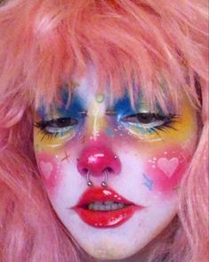 a close up of a person with makeup and pink hair wearing clown make - up