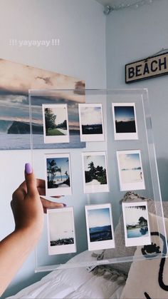 a person pointing at pictures on a wall in a room with blue walls and white bedding