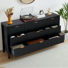 a record player is sitting on top of a black cabinet next to a potted plant