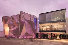 a large building with purple lights on it's side and a person walking in front