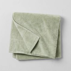 a green towel folded on top of a white wall