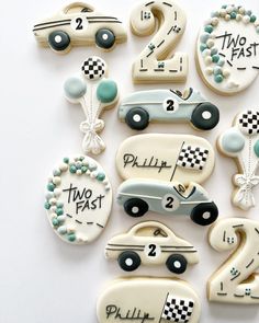 decorated cookies with cars and numbers are displayed on a white table top, including two pastries