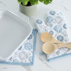 two wooden spoons sitting on top of a blue and white napkin next to a potted plant