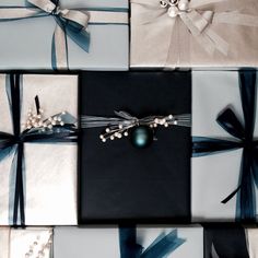 presents wrapped in blue and white paper with pearls, bows and ribbons on them are shown