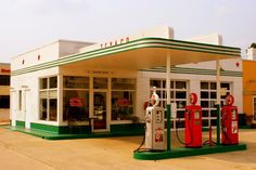 an old gas station with two red and green pumps