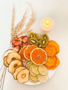 an assortment of fruits and vegetables on a plate with a lit candle in the background