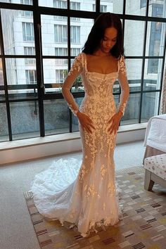 a woman in a wedding dress standing by a window