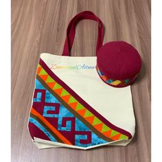 a red hat is sitting on top of a white tote bag with colorful designs