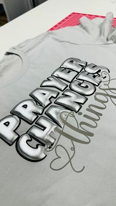 a t - shirt with the words bravo written in silver foil on it, sitting on top of a table