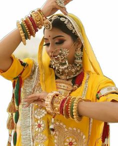 a woman in a yellow outfit with jewelry on her neck and hands behind her head